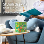 Relaxing reading scene with a colorful Kleenex cube tissue on a coffee table and a person holding a notebook