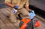 Kneeling person applying GUNK degreaser to an orange garden tool while holding a blue rag