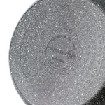 Textured speckled cookware base with embossed Korkmaz brand mark and circular pattern on the underside.