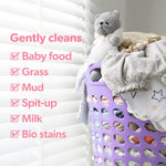 Laundry basket filled with baby clothes and a knit toy beside text listing types of stains Dreft gently cleans