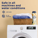 Laundry room scene with a front-load washer, folded towels in a wicker basket and a Downy Blends toasted vanilla bottle with safety text.