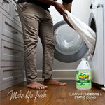 Laundry room scene with person loading a washer and an OdoBan gallon jug placed on the floor beside the machine.