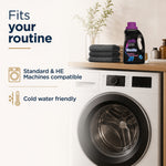 Laundry room scene with washing machine, folded towels and a Woolite Darks Defense bottle with text about machine compatibility
