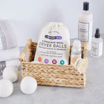 Laundry 360 canvas bag of dryer balls displayed in a woven basket with towels and laundry bottles styled around it