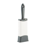 Gray-handled lint brush inserted upright into a white and gray self-cleaning base on white background