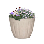 Sand-colored planter filled with mixed flowering plants, showing textured fluted exterior