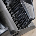 Close macro of black Libman broom bristles seated in the dustpan teeth and plastic dustpan rim