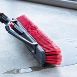 Close-up of Libman red bristles and squeegee edge pushing water on a concrete floor