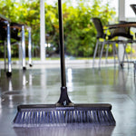 Libman broom upright on a tiled indoor floor with handle and bristles visible in a bright room setting