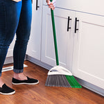 Lifestyle image of someone using a Libman angled broom with green handle to sweep a wood floor near white cabinets.