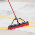 Libman push broom with red bristles sweeping painted yellow lines on a concrete surface