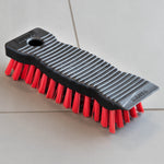 Libman black scrub brush with red bristles resting on light gray tiled floor