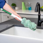 Person holding bundled Libman green-and-white mop head near a kitchen sink and faucet