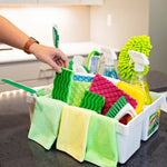 White Libman cleaning caddy filled with colorful microfiber cloths, brushes and spray bottles on a kitchen counter with a hand reaching in