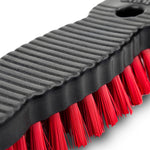 Tight macro of the ribbed black handle edge and red nylon bristles of a Libman scrub brush