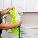 Hands attaching or removing a bright green chenille microfiber refill from a white mop frame