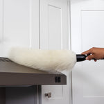 Hand using a Libman lambswool duster to clean the top of a kitchen range hood in a lifestyle setting