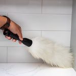 Person holding a Libman lambswool duster to dust a kitchen backsplash and countertop corner