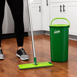 Libman green mop, handle and tall dual-chamber bucket positioned on a kitchen floor with cabinets in the background