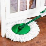 Close-up of a Libman spin mop head cleaning along a cabinet baseboard on a hardwood floor.