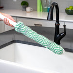 Close-up of twisted green-and-white mop head held above a kitchen sink area