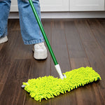Person using a green-handle mop with bright green chenille refill on a dark wood floor