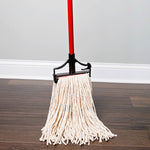 Libman mop mounted on a red handle and black clip, standing on a dark wood floor with the cream-colored yarn strands spread downward.
