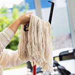 Hands attaching a Libman cut-end mop refill to a black clip attachment, showing the mop strands and part of a red handle in a bright room.