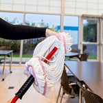 Hand holding a white cotton mop head being attached to a red mop handle in a classroom or office setting