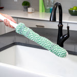Angled view of Libman mop handle with green-and-white refill extended over a kitchen sink faucet, showing mop attachment