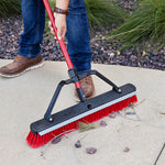 Libman red-handle push broom sweeping small rocks and pine needles on sidewalk