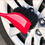 Red Libman brush head being used to clean the spoke area of a vehicle wheel