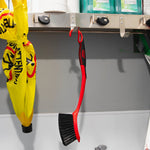 Libman red scrub brush hanging from a hook in a utility space beside supplies