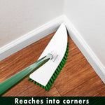 Libman scrub head with green bristles and green handle reaching into a room corner on a wood-look floor