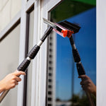 Reflective-window lifestyle photo of a Libman squeegee and red-mesh sponge head with textured grip being used to clean glass.