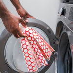 Hands placing a Libman Wonder Mop head into the drum of a front-load washing machine