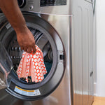 Hand lowering a patterned Libman Wonder Mop head into the open door of a front-load washer