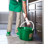 Person rinsing a Libman Wonder Mop into a green Libman-branded bucket on a kitchen floor