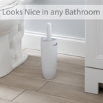 Bath Bliss white contour toilet brush and holder placed on a bathroom floor next to a toilet, overlaid text reads "Looks Nice in any Bathroom"