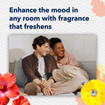 Lifestyle image with smiling couple on a couch and headline about enhancing the mood with fragrance, framed by hibiscus and pineapple art
