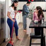 Lifestyle kitchen scene with a person sweeping popcorn debris using a red O-Cedar broom while family members stand nearby