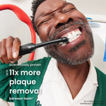 Person brushing teeth with a black Quip electric toothbrush in a lifestyle shot with overlay text about plaque removal