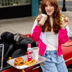 Lifestyle image of a woman leaning on a red convertible with a tray of food and a Citrus Magic Dragonfruit spray bottle visible