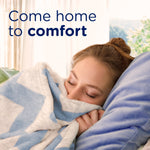 Person cuddling a soft blanket with text reading 'Come home to comfort' in a lifestyle scene implying fresh laundry