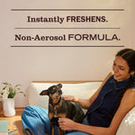 Woman sitting on a couch petting a small dog with headline text reading instantly freshens and non-aerosol formula above.