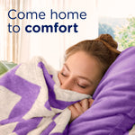 Woman cuddling a purple blanket with text 'Come home to comfort' in a lifestyle image