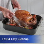 Hands lifting a clear oven bag from a roasting pan to reveal a cooked turkey inside the bag
