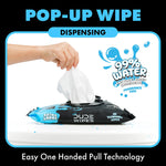Hand pulling a pop-up LiL' Dude wipe from a black pack demonstrating one-handed dispensing and 99% water callout