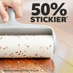 Hand-held lint roller picking up seeds and debris from a hardwood floor with large “50% stickier” text