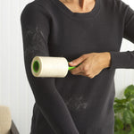 Person using Evercare green-handled lint roller on a black sweater showing removed pet hair